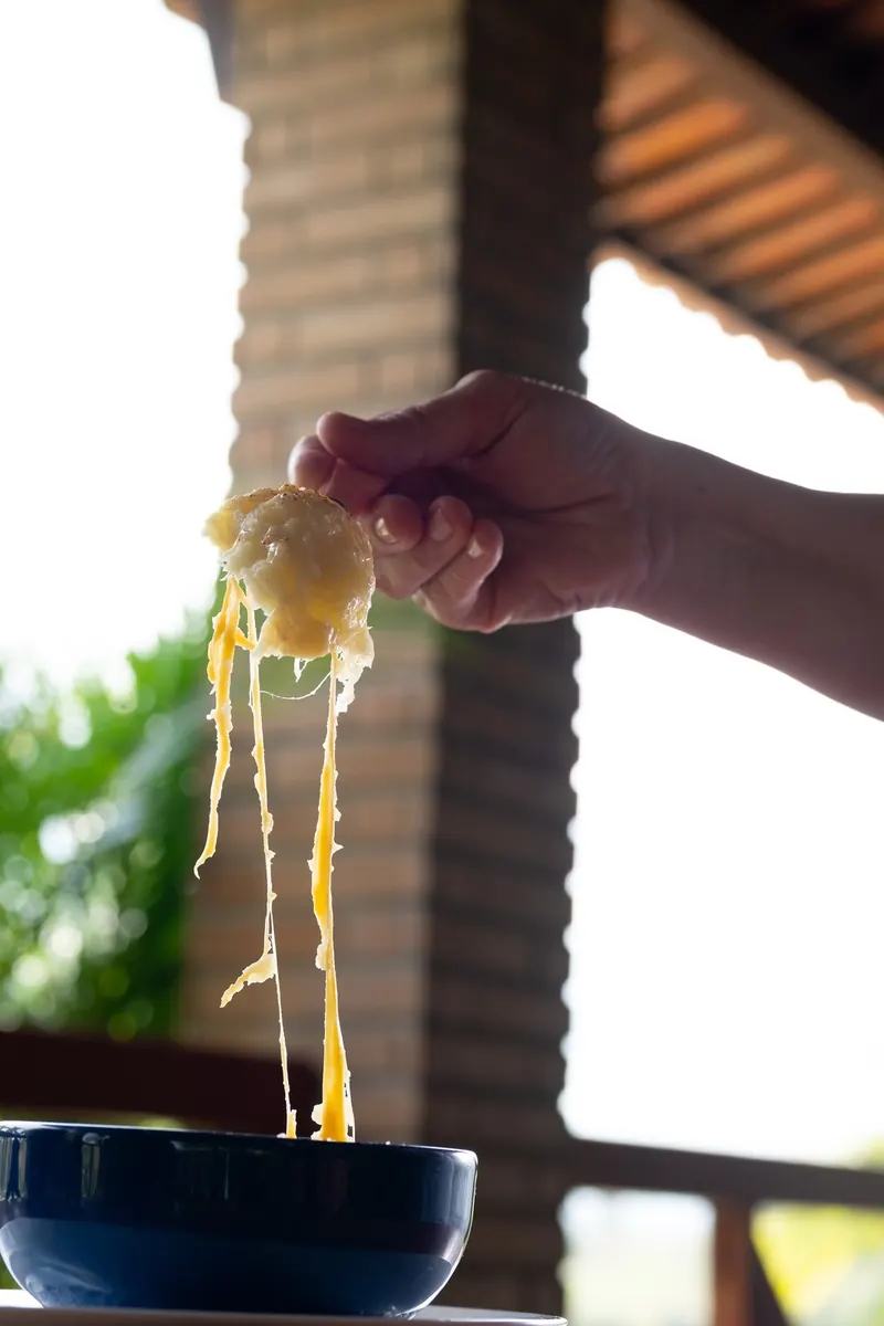 Queijo derretido sendo puxado em fios de uma tigela