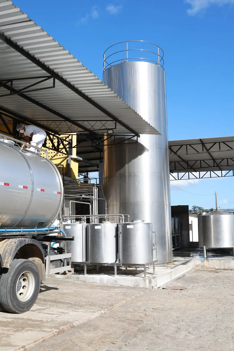 Silos de inox e caminhão-tanque na área de recepção de leite da fábrica